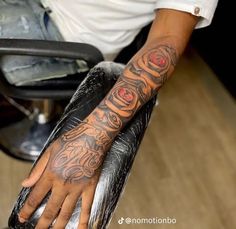 a man with a tattoo on his arm is sitting in a barbershop and holding onto the chair