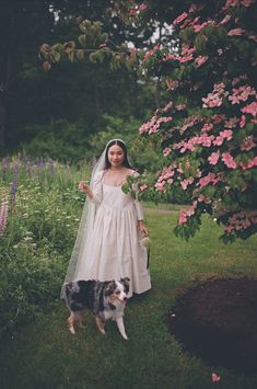 a woman in a wedding dress standing next to a dog