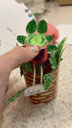 a person is holding a paper cut out of a potted plant