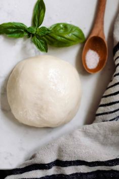 a ball of dough next to a wooden spoon on a white surface with black and white stripes