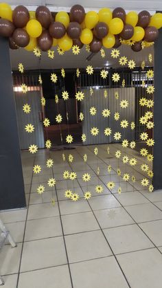 some balloons are hanging from the ceiling with yellow flowers on them and brown balls in the air