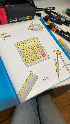 a person holding a notebook with an image of a calculator and pencils