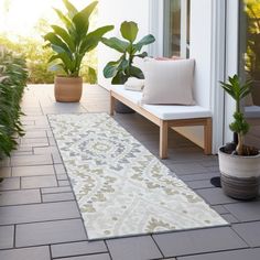 a white rug on a patio with potted plants next to it and a bench in the background