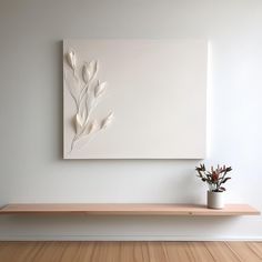 a white vase with some flowers on top of a wooden shelf next to a painting