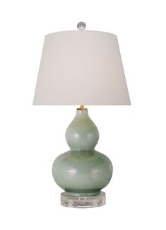 a green table lamp with a white shade on the base and a light bulb in the middle