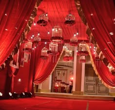 a room with red curtains and chandeliers hanging from the ceiling