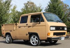 a tan truck parked in a parking lot next to trees