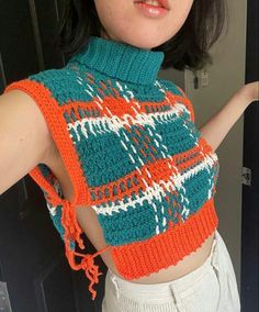 a woman wearing an orange and blue knitted top with her hand on her hip