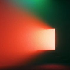 an open door in the middle of a room with red and green light coming from it