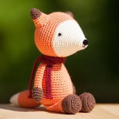 a crocheted stuffed animal sitting on top of a wooden table next to a green background