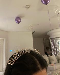 a woman wearing a tiara with balloons hanging from the ceiling