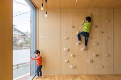 two children climbing up the side of a wooden wall