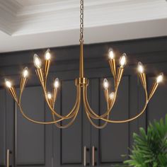 a chandelier hanging from the ceiling in a kitchen with cabinets and potted plant