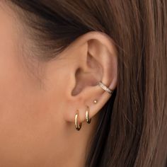 a close up of a woman's ear with two small gold hoops on it