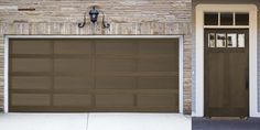 a brown garage door is open in front of a brick house