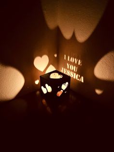 an illuminated box sitting on top of a table next to some paper cut out hearts