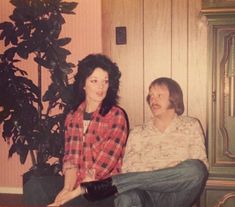 two people sitting next to each other near a plant