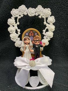 a wedding cake topper with a bride and groom sitting in a chair on it