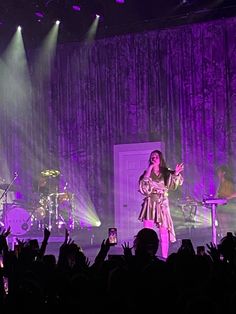 a woman standing on top of a stage in front of a crowd at a concert