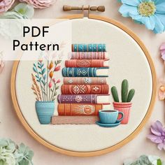 a cross stitch pattern with books and plants on it, in front of some flowers