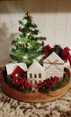 a small christmas tree in a wooden bowl with houses on it and decorations around the base