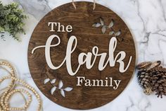 a wooden sign that says the clark family on it next to pine cones and beads