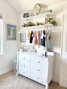 a white dresser with clothes hanging on it