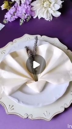 a white plate with some flowers on top of it and a purple table cloth in the middle