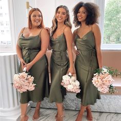 three beautiful women standing next to each other holding bouquets