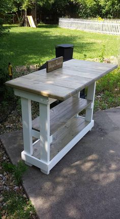 a white table sitting in the middle of a yard next to a black trash can