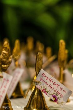 small gold figurines with cards on them sitting on a white tablecloth covered table