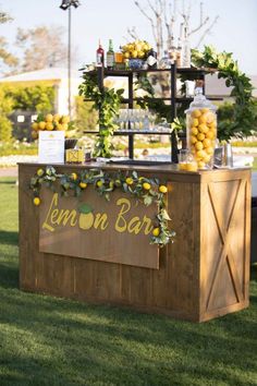 an outdoor bar with lemons and drinks on the top, surrounded by greenery