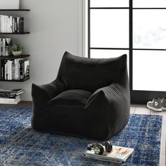 a living room with a blue rug, black chair and bookshelf on the floor