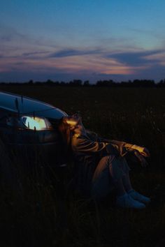 a person laying on the ground next to a car with their head in the hood