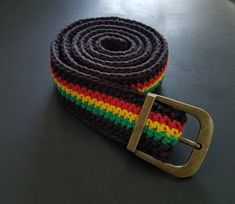 a multicolored knitted belt with a metal buckle on a black table top