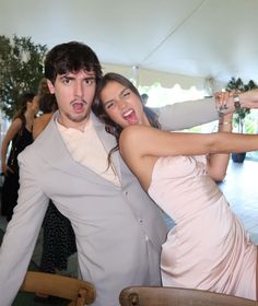 a man and woman pose for a photo in front of a crowd at a party