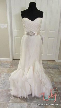 a white wedding dress on display in front of a door with a black mannequin