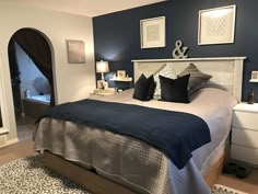 a bedroom with blue walls and white bedding has black pillows on the headboard