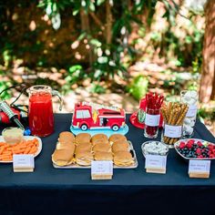 a table topped with sandwiches and veggies on top of a blue table cloth