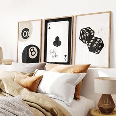 a bed topped with lots of pillows next to two framed pictures