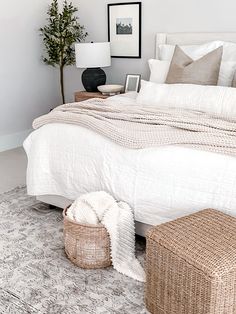 a bed with white linens and pillows in a bedroom next to a small tree