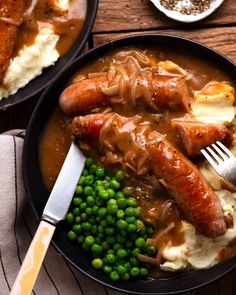 a plate with peas, mashed potatoes and two sausages in gravy