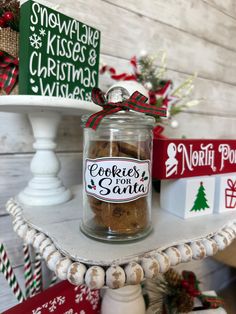 a glass jar filled with cookies sitting on top of a white table next to christmas decorations