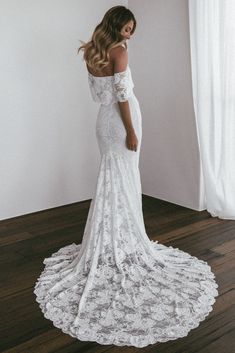 a woman in a white wedding dress standing on a wooden floor with her back to the camera