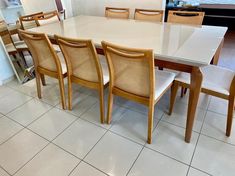 a dining room table with six chairs and a white tile floor in front of it