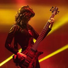 a woman holding a bass guitar on stage