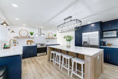 a large kitchen with blue cabinets and white counter tops, along with bar stools