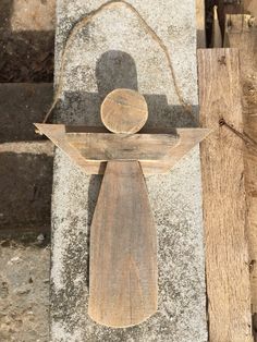 a wooden angel hanging on a stone wall