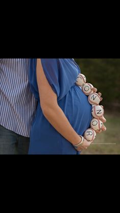 a pregnant woman holding baseballs with the word now spelled on it's belly