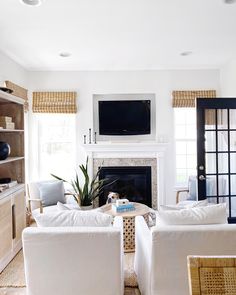 a living room filled with furniture and a flat screen tv mounted on the wall above a fire place